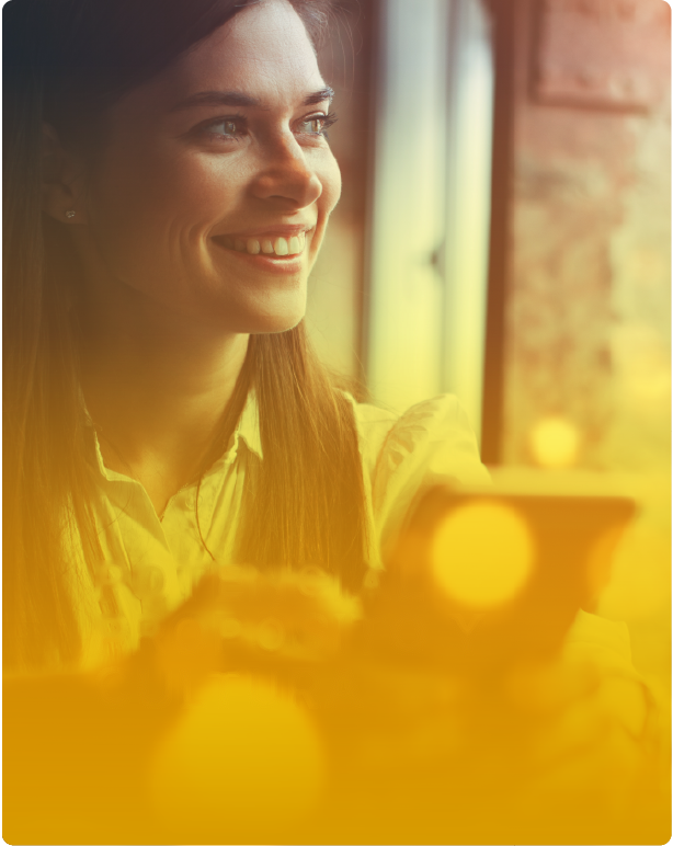 Mujer sonriendo mirando por una ventana con luz cálida, representando potencial, propósito y cultura organizacional