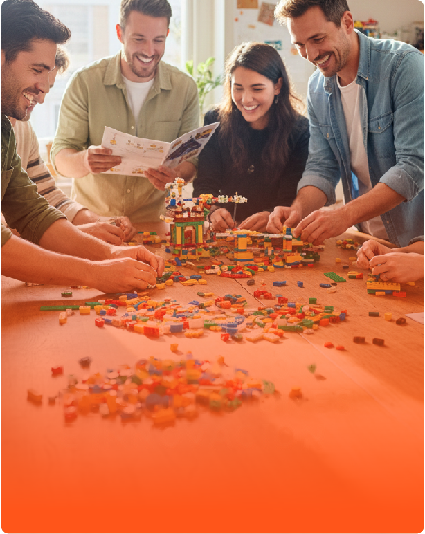 Grupo de personas construyendo con piezas de juego sobre una mesa, representando co-creación de soluciones e innovación
